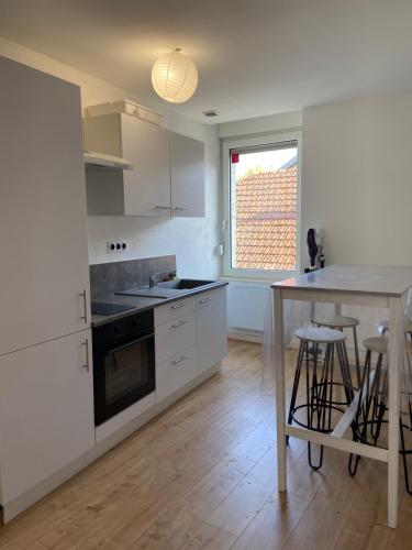 une cuisine avec des armoires blanches et une table avec des tabourets dans l'établissement le repos vésulien, à Navenne