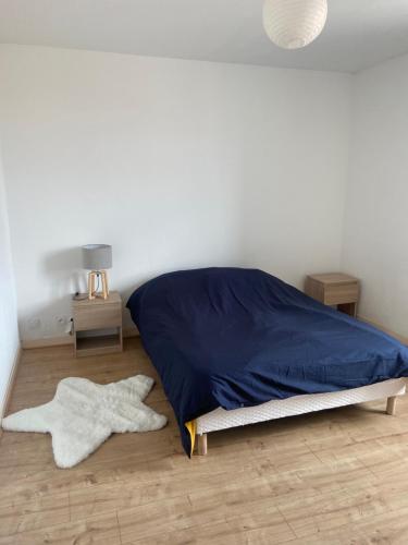 Cette chambre comprend un lit avec des draps bleus et du parquet. dans l'établissement le repos vésulien, à Navenne