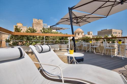 a rooftop patio with white chairs and an umbrella at Ursulino Valletta in Valletta