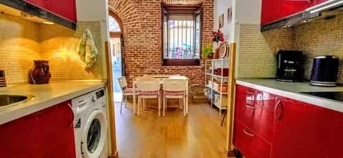 une cuisine avec des placards rouges, une table et des chaises dans l'établissement Apartamento Lavapies al lado del Rastro, à Madrid