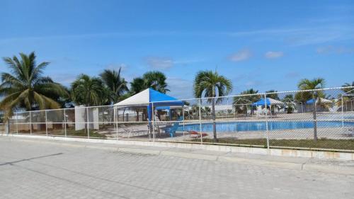 a fence around a pool with a tent and palm trees at Villa marina, santa elena in Santa Elena
