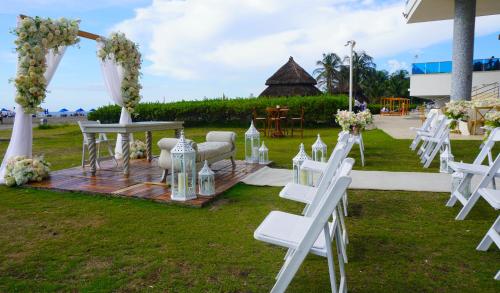 a wedding ceremony with white chairs and a table at Hotel Las Americas Casa de Playa in Cartagena de Indias