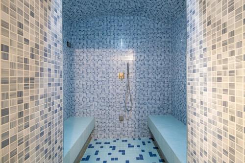 La salle de bains est pourvue de carrelage bleu, d'une douche et de 2 toilettes. dans l'établissement Colonno Penthouse, à Colonno