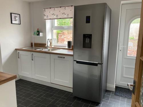 a kitchen with a stainless steel refrigerator and a sink at Marni’s Cottage - Rural location & fell views in Frizington