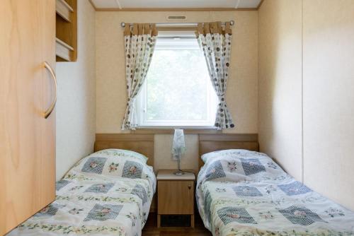 two beds in a small room with a window at Mobile home in Sjöared in Markaryd