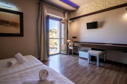 a bedroom with a bed and a desk with a television at Hotel Villa De Setenil in Setenil