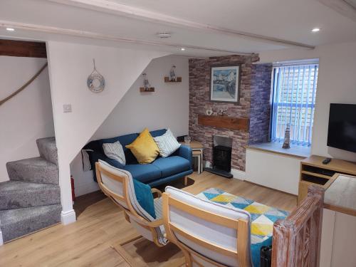 a living room with a blue couch and a fireplace at Cheerful Fisherman,s Cottage in St Ives