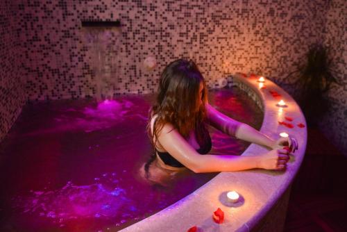 una donna seduta in una vasca da bagno con luci viola di Agriturismo Airone a Pitigliano
