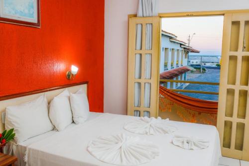 um quarto com uma cama branca e uma varanda em Garça Branca Praia Hotel em Porto Seguro