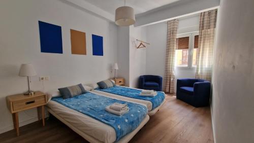 a bedroom with a bed and two blue chairs at IMEDA REYES CATÓLICOS in Granada