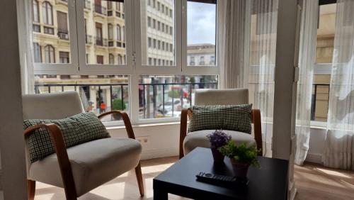 a living room with two chairs and a table and windows at IMEDA REYES CATÓLICOS in Granada