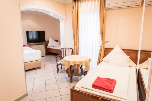 pokój hotelowy z łóżkiem i stołem oraz pokój w obiekcie Kaiser Panzió w mieście Baja