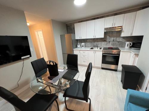 a kitchen with white cabinets and a glass table and chairs at Le Centre-Ville in Rouyn