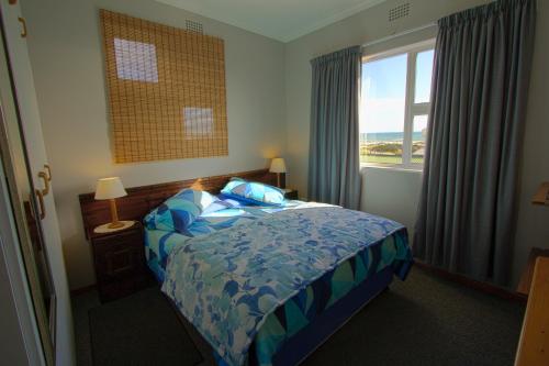 a bedroom with a bed and a large window at Lekke Ekke in Lambertʼs Bay