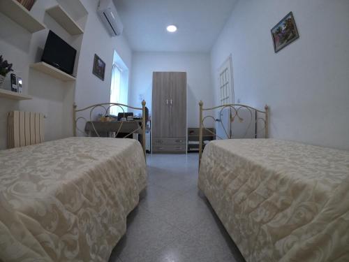 a bedroom with two beds and a table and a window at Ostello Villafranca in Pignola