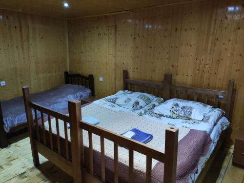 a bedroom with two beds and wooden walls at mariami in Stepantsminda