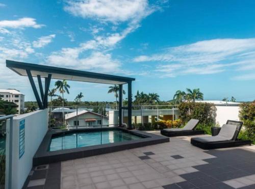 a patio with a swimming pool and two lounge chairs at Airtrip Apartments on River Street, Mackay in Mackay