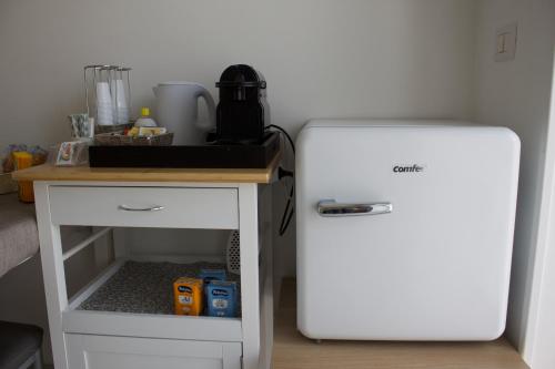 a small white refrigerator next to a small table at Ostello Villafranca in Pignola