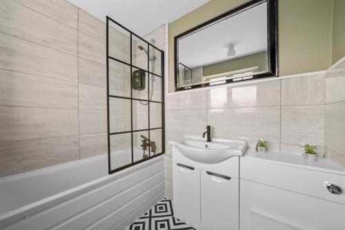 納尼頓的住宿－BridgeCity Cheerful 3 bedroom home in Nuneaton，浴室配有盥洗盆、镜子和浴缸