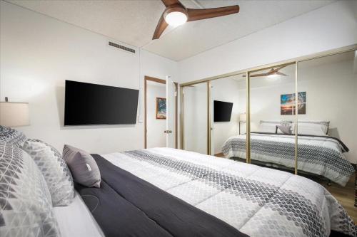 a bedroom with two beds and a flat screen tv at Kona Plaza 210 in Kailua-Kona