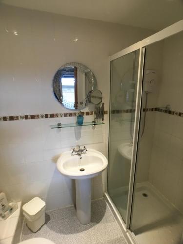 a white bathroom with a sink and a shower at Ty Rosa Rooms in Cardiff