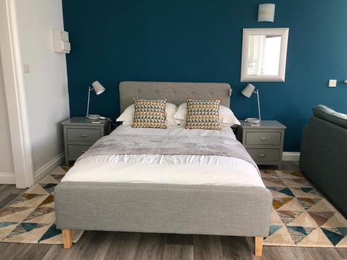 a bedroom with a large bed with blue walls at Little Valley View in Otterham