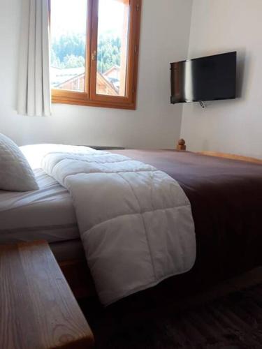 une chambre avec un lit avec une télévision au mur dans l'établissement T2 Les orres 1800 pied des pistes avec piscine, aux Orres