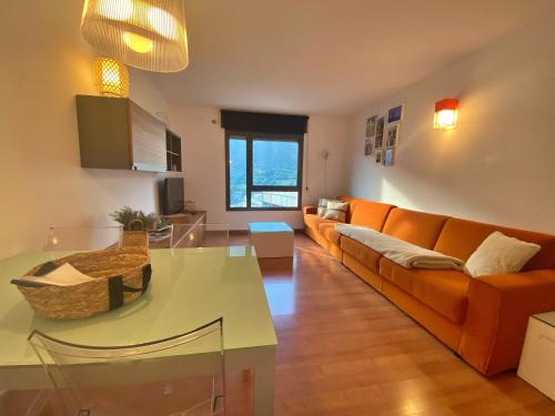 a living room with an orange couch and a table at Tucamp 3,7 a 30 mts de Funicamp in Encamp