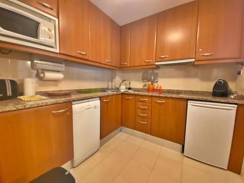 a kitchen with wooden cabinets and white appliances at Tucamp 3,7 a 30 mts de Funicamp in Encamp