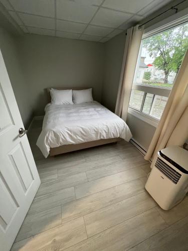 a small bedroom with a bed and a window at Le Centre-Ville in Rouyn