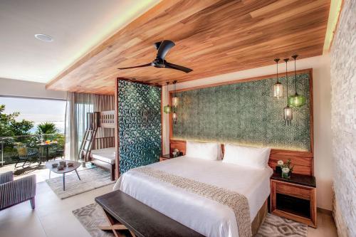 a bedroom with a large bed and a balcony at Palmaïa The House of AïA All Inclusive Wellness Resort in Playa del Carmen