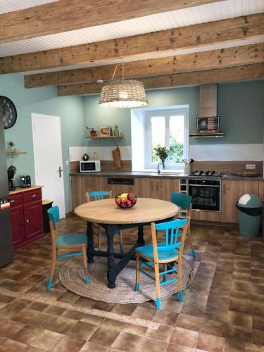- une cuisine avec une table en bois, des chaises et un bol de fruits dans l'établissement Longère bretonne chaleureuse près de la mer, à Yvias