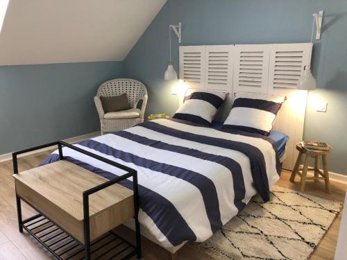ein Schlafzimmer mit einem großen Bett und einem Stuhl in der Unterkunft Longère bretonne chaleureuse près de la mer in Yvias