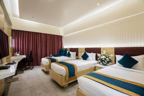 a hotel room with two beds and a desk at Zion - A Luxurious Hotel in Bangalore