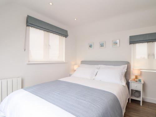 a bedroom with a white bed and two windows at Marazion Attic in Marazion