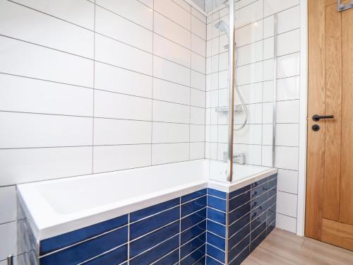 a bathroom with blue and white tiles and a tub at Marazion Attic in Marazion