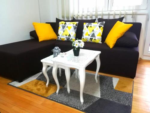 a black couch with yellow pillows and a white table at Sweet dreams in Bijeljina