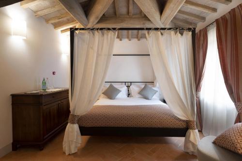 1 dormitorio con cama con dosel y cortinas en Tenuta CastelGiocondo en Montalcino