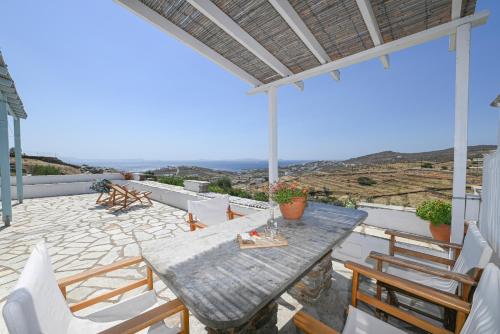 a table and chairs on a patio with a view at Αστραία - με θέα στο Αιγαίο in Agios Ioannis