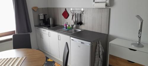 uma pequena cozinha com armários brancos e um lavatório em Studio-Apartment Braunschweig in Wolfenbüttel em Volfembutel