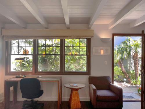 Una habitación con dos sillas y una mesa y ventanas. en Casa Del Mar Inn, en Santa Bárbara