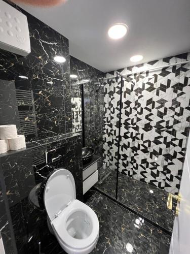 a bathroom with a toilet and black and white tiles at Yoa apartaments in Deva