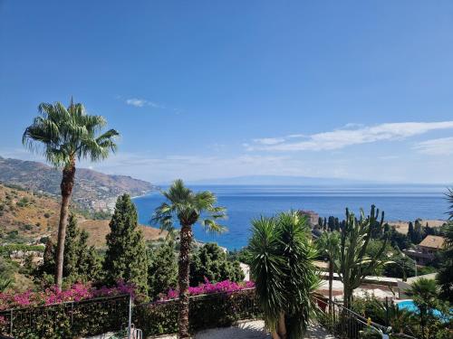 uma vista para o oceano a partir de um resort com palmeiras em Taormina Bella Vista Apartment in center with pool by Taormina Holidays em Taormina