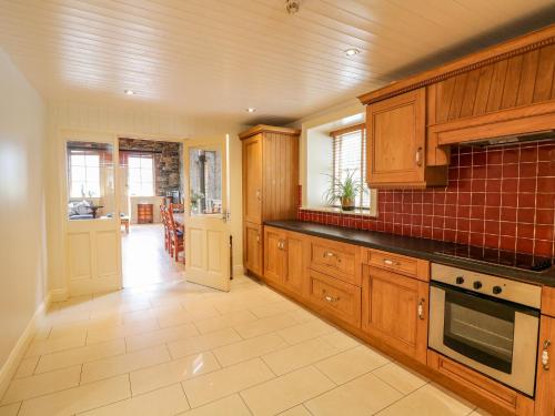 a kitchen with wooden cabinets and a tile floor at Coach House in Portlaoise