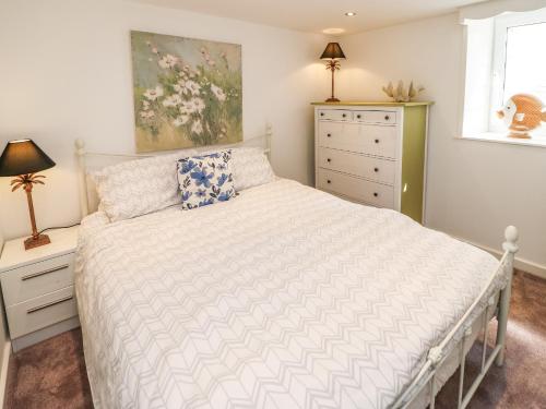 a bedroom with a bed and a dresser and a window at Beneath The Beams in Glossop