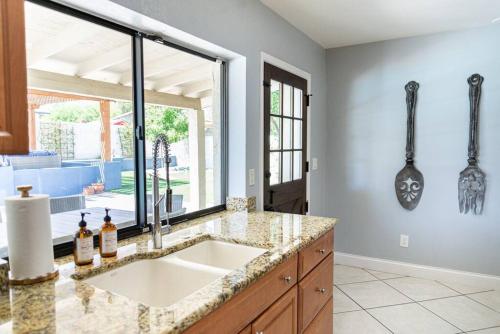 a kitchen with a sink and a large window at Sunnyside of Life Retreat: Serene 5 BR with pool in Phoenix