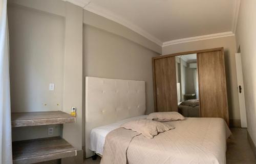 een kleine slaapkamer met een bed en een spiegel bij Ap à 170m do mar, Praia dos Ingleses in Florianópolis