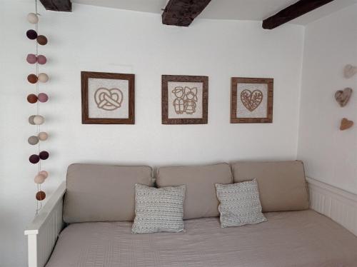 - un canapé dans une chambre avec quatre photos sur le mur dans l'établissement Gîte Cerise & Coquelicot, à Epfig