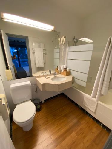 a bathroom with a toilet, sink, and tub at Savoie Hotel aux portes de Genève in Saint-Julien-en-Genevois