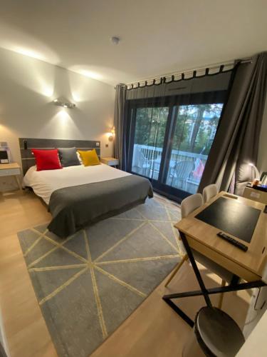 a bedroom with a bed and a desk at Savoie Hotel aux portes de Genève in Saint-Julien-en-Genevois